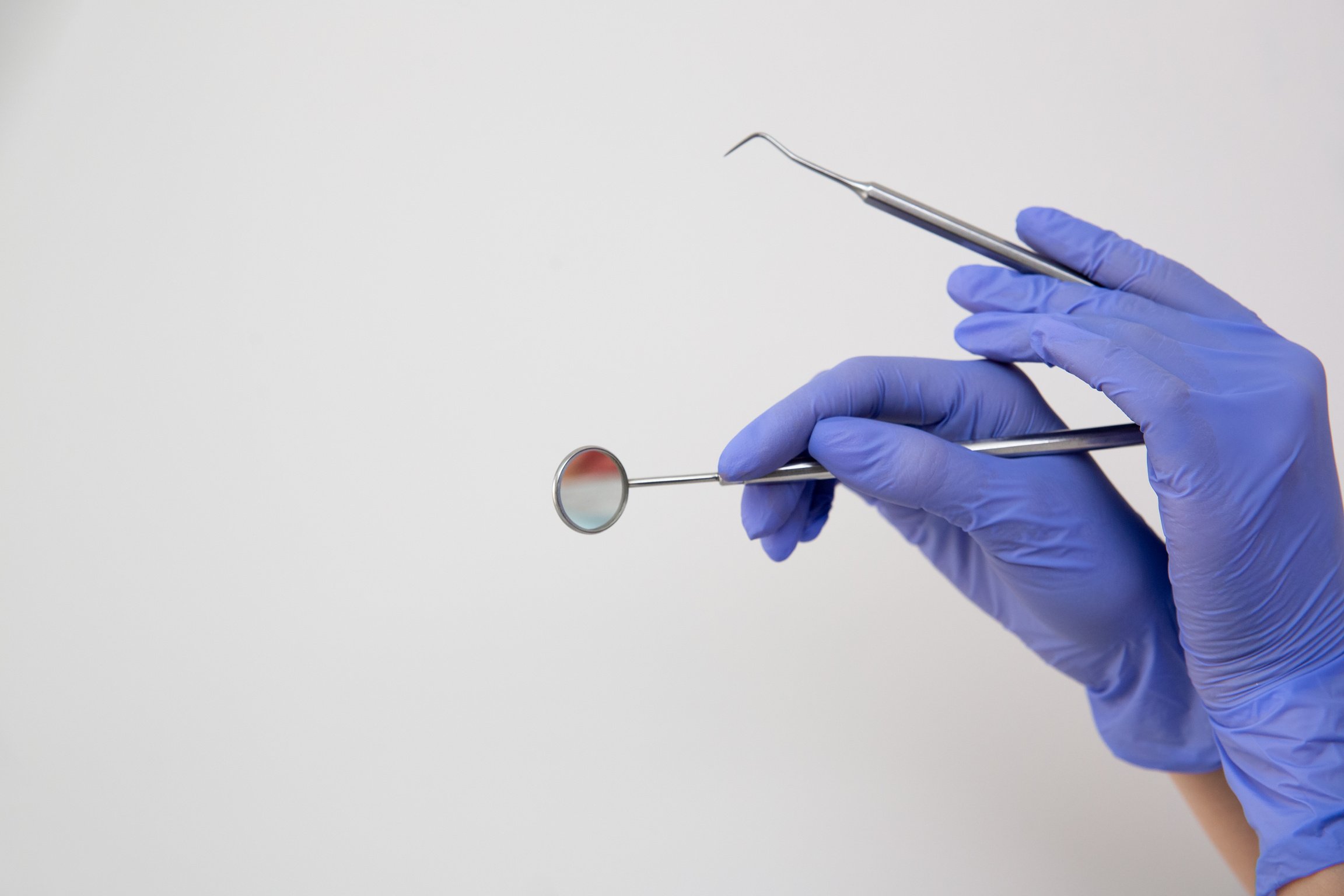 Crop hand of dentist in gloves with instrument for treatment